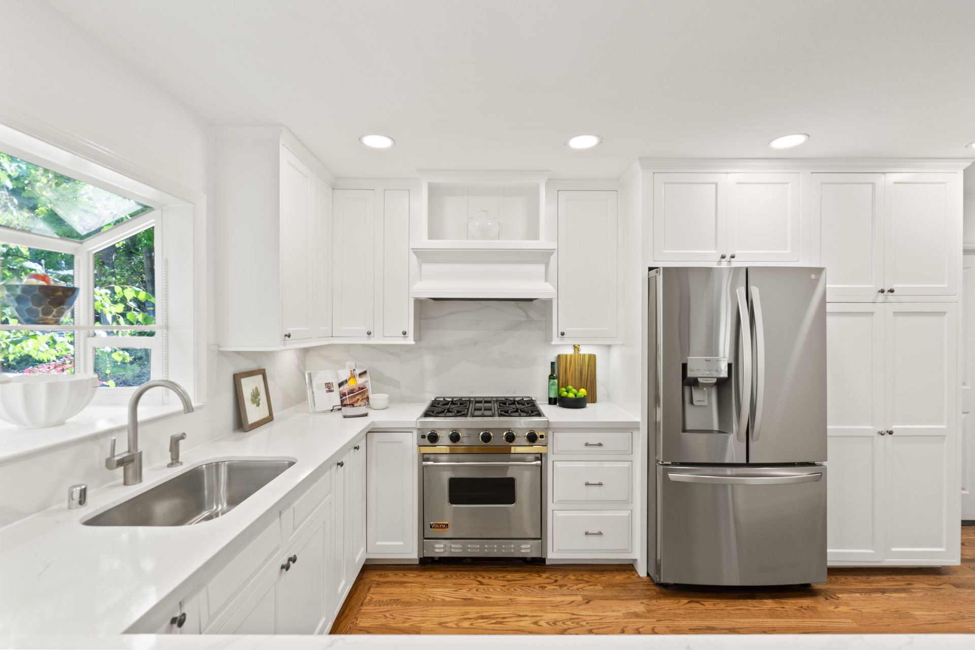 A kitchen with white cabinets , stainless steel appliances , a sink , and a refrigerator.