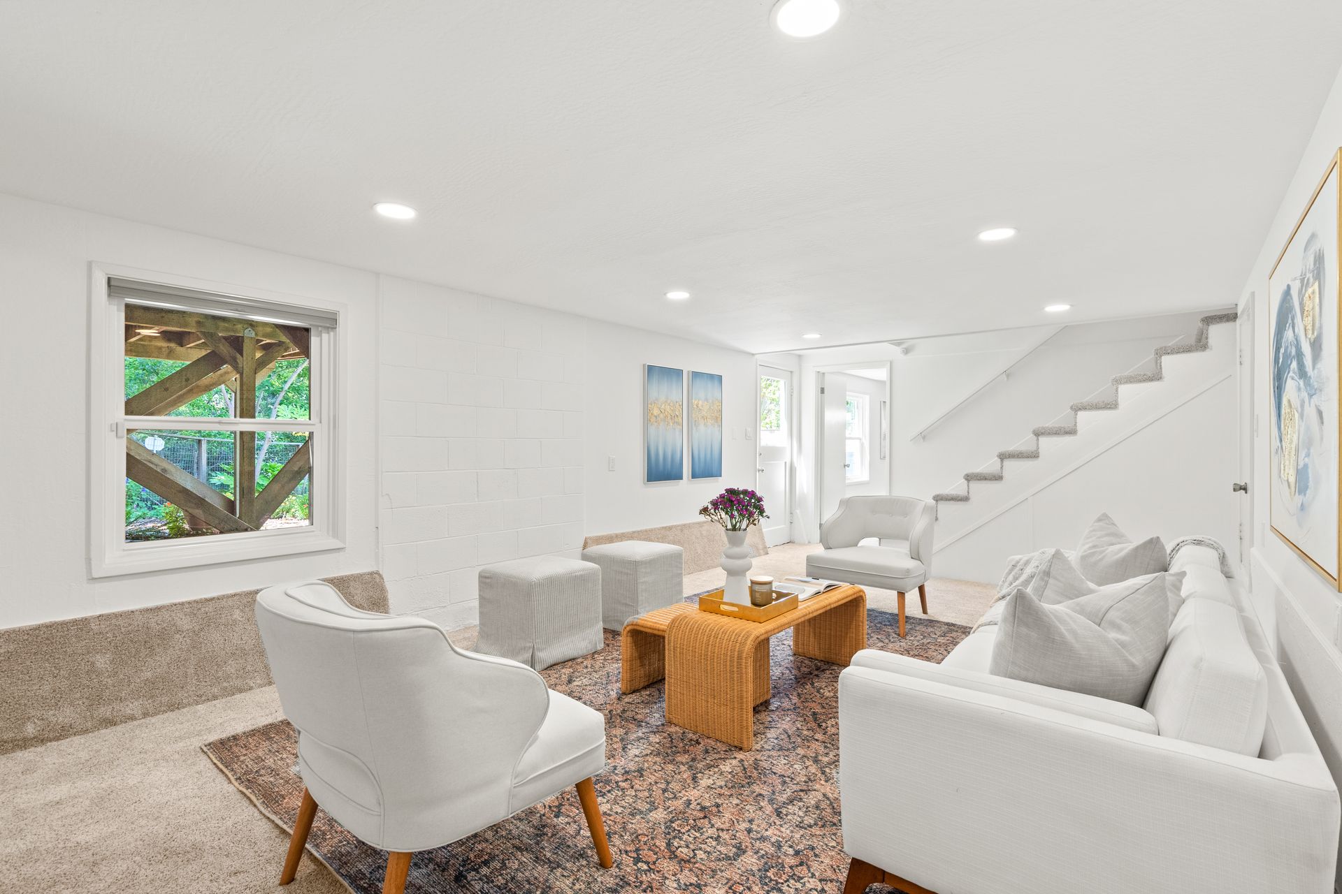 A living room with a couch , chairs , coffee table and stairs.