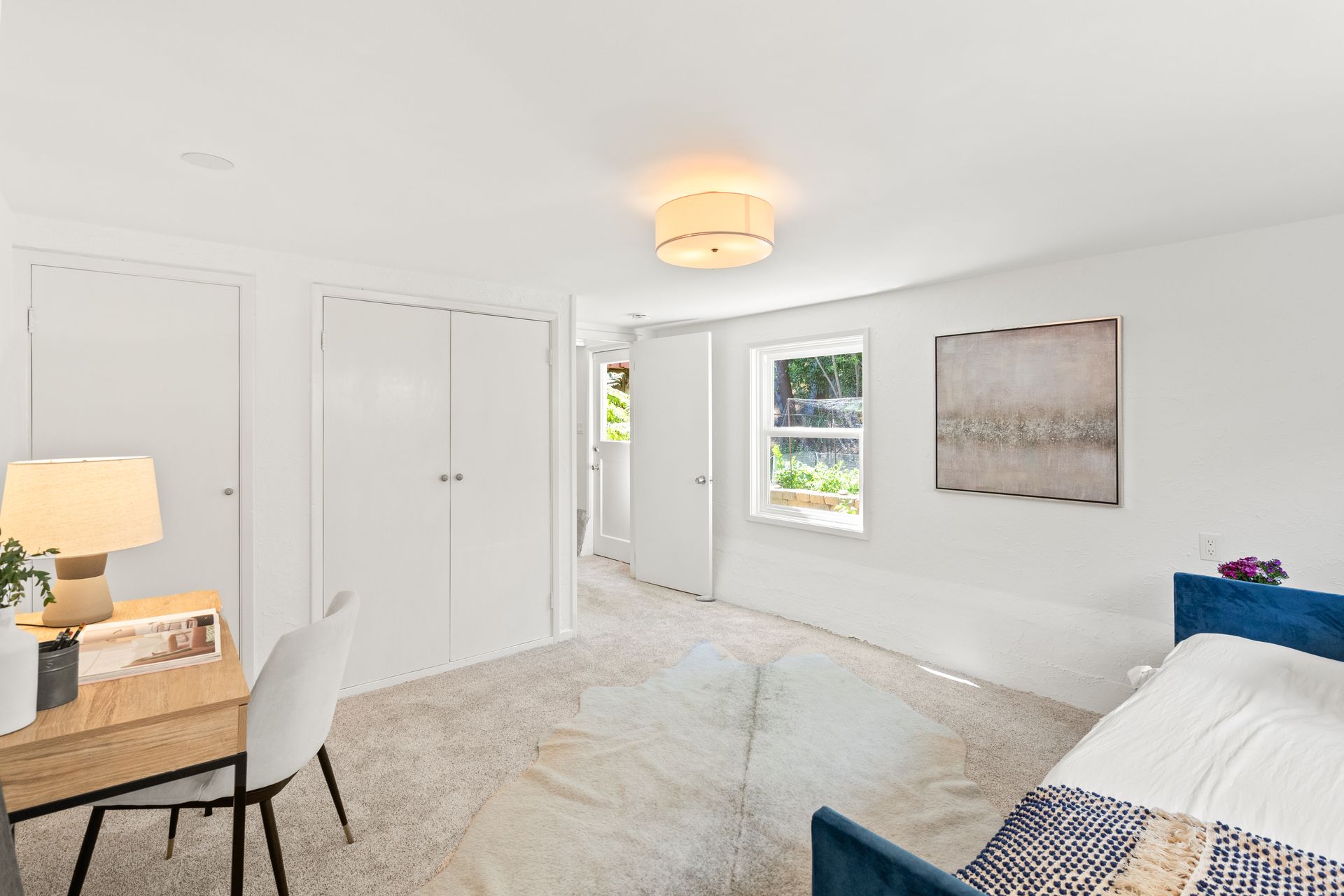 A bedroom with a bed , desk and chairs.