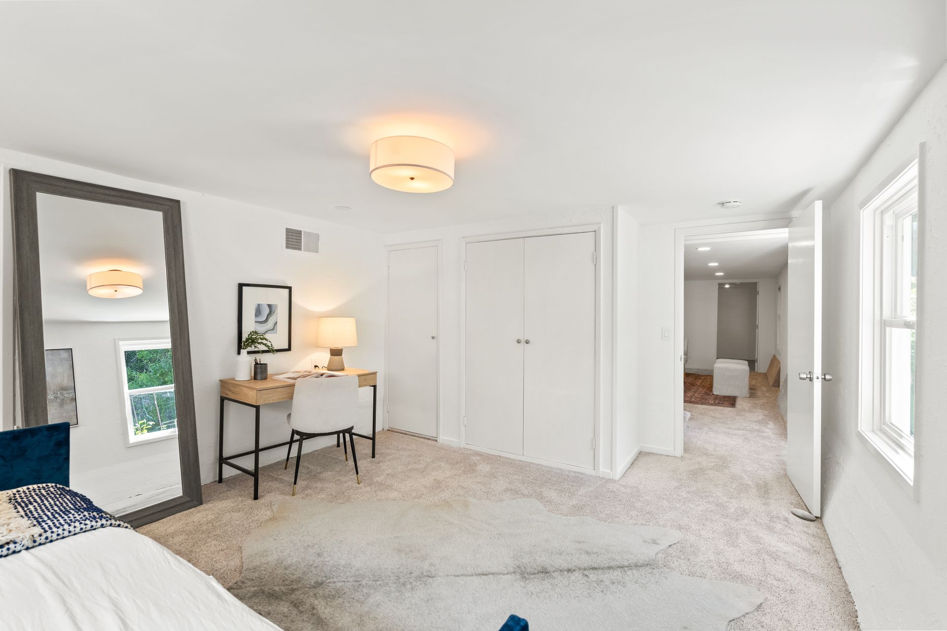 A bedroom with a large mirror and a desk.