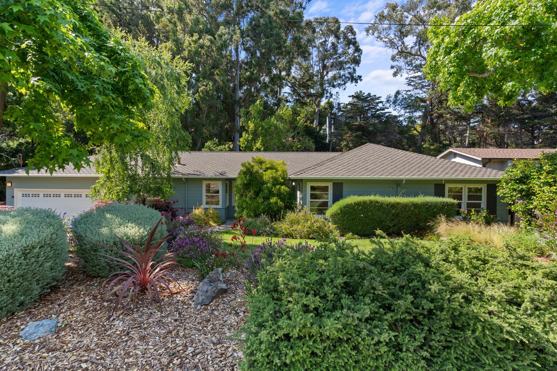 A house with a brown roof is surrounded by trees and bushes.