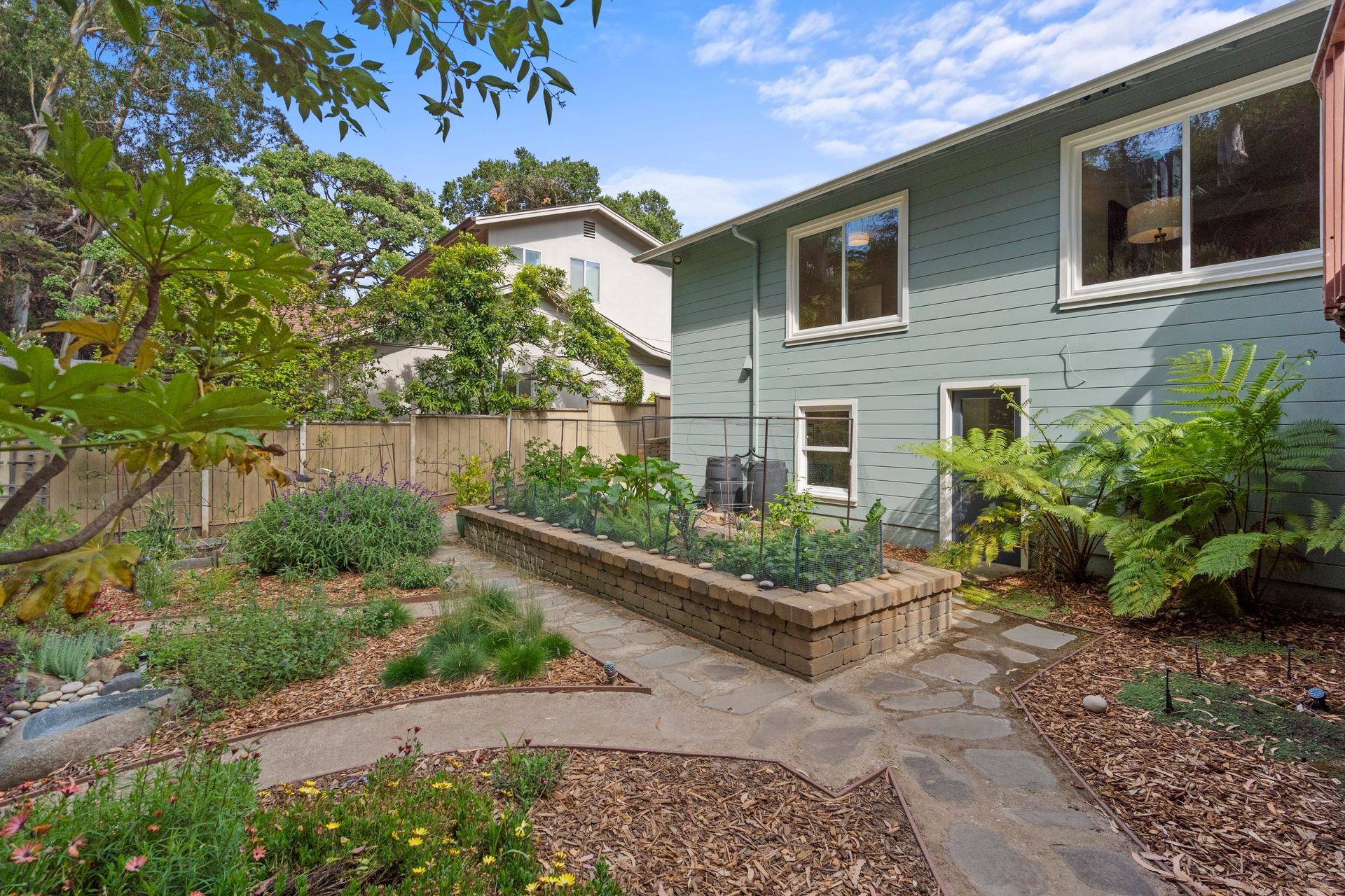 A house with a garden in front of it and a walkway leading to it.