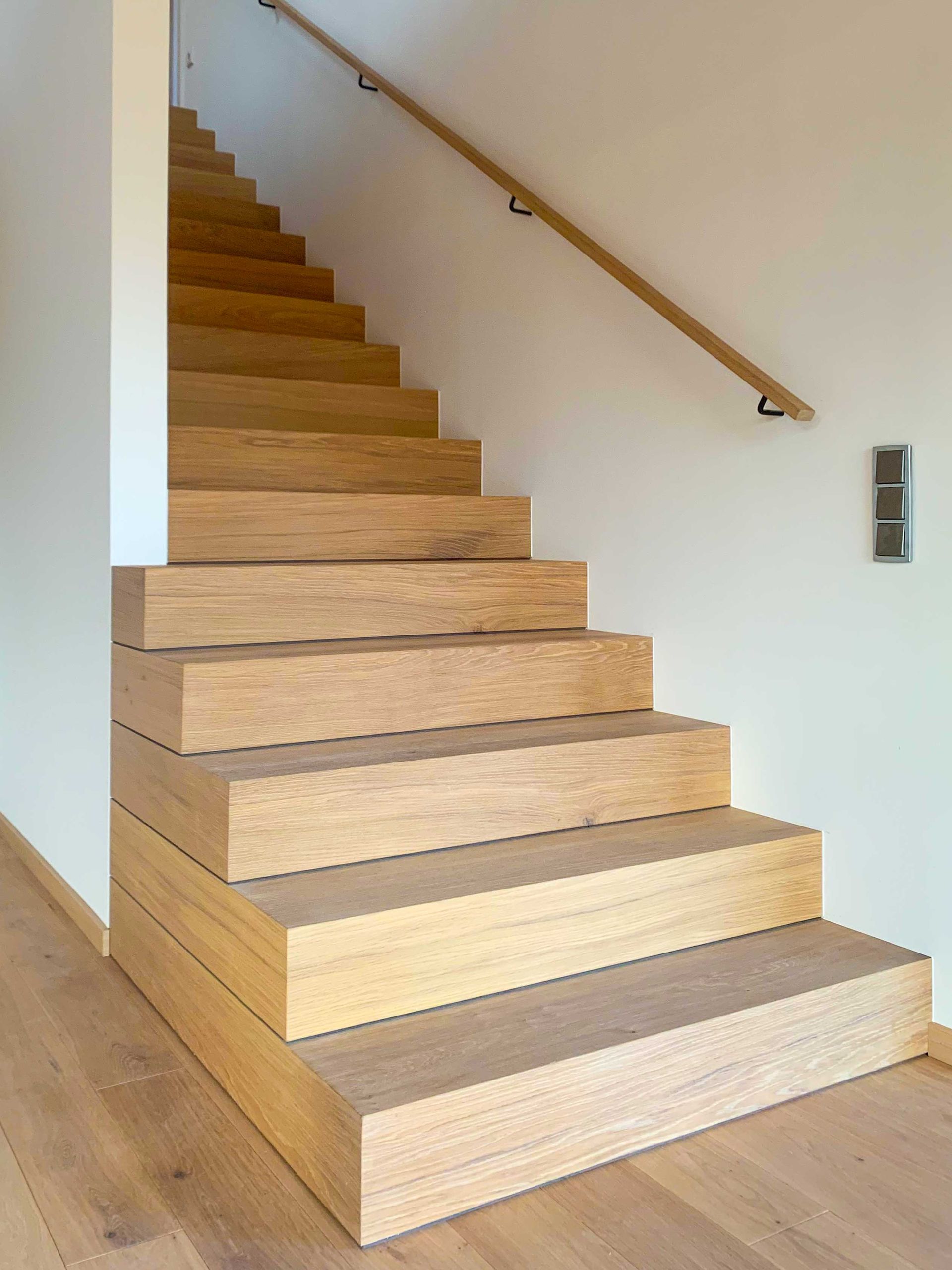 Holztreppe mit Handlauf in einem hellen Flur