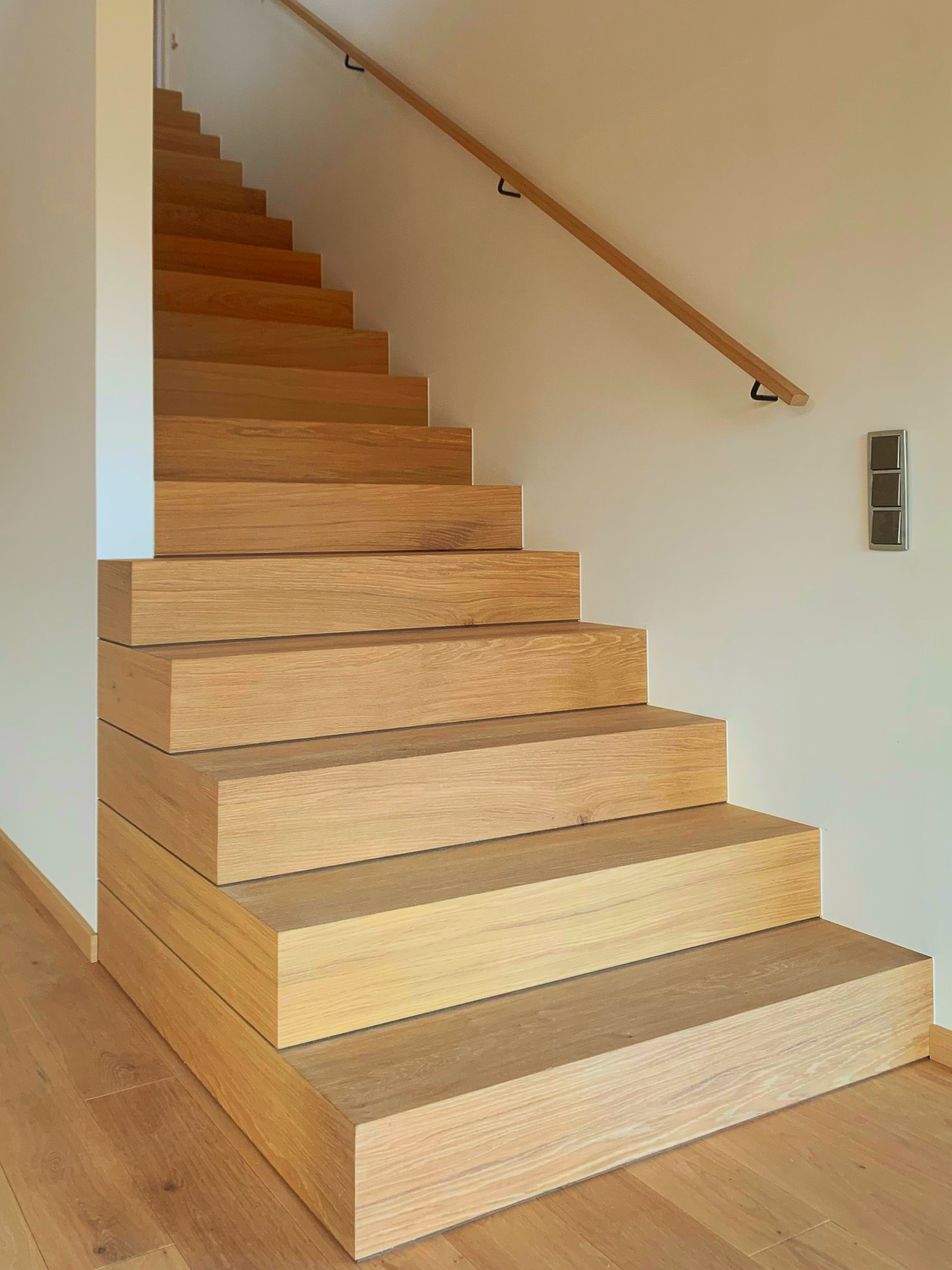 Holztreppe mit Handlauf in einem hellen Innenflur