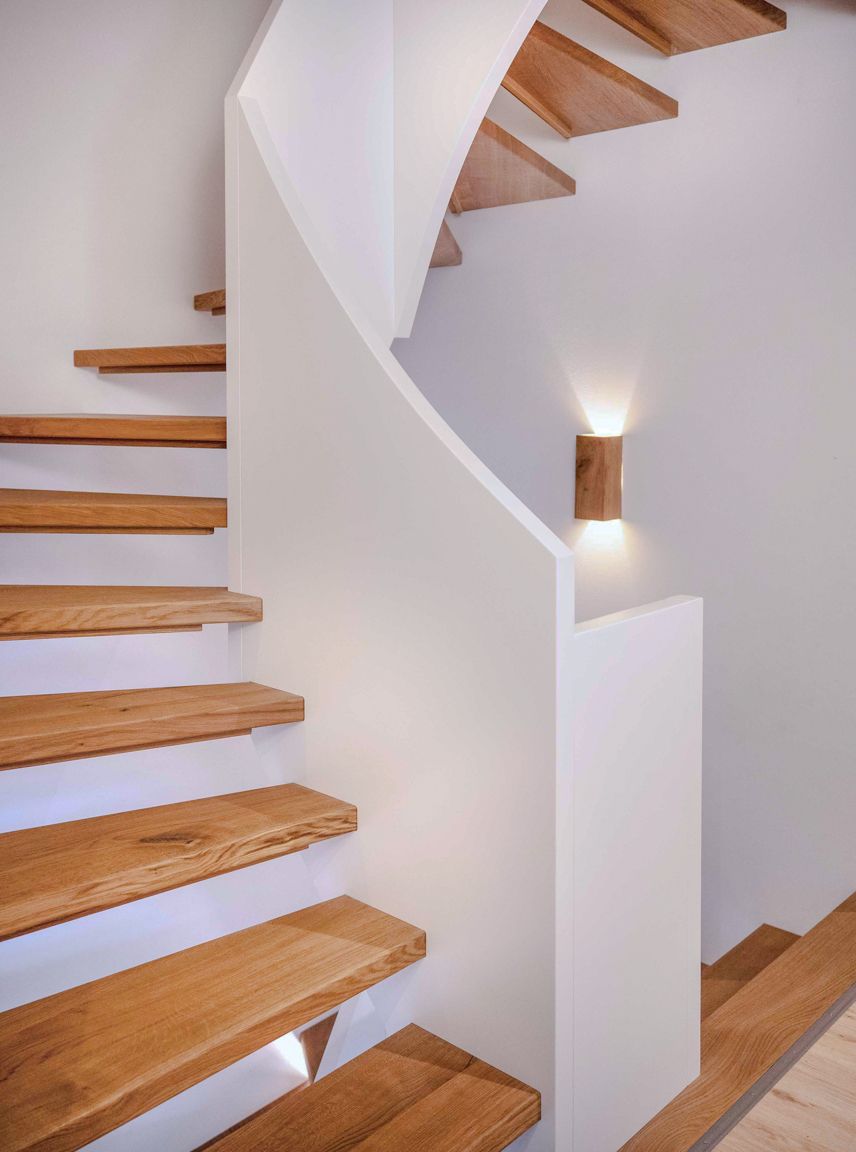 Geschwungene weiße Treppe mit Holzstufen und Wandbeleuchtung in einem modernen Interieur