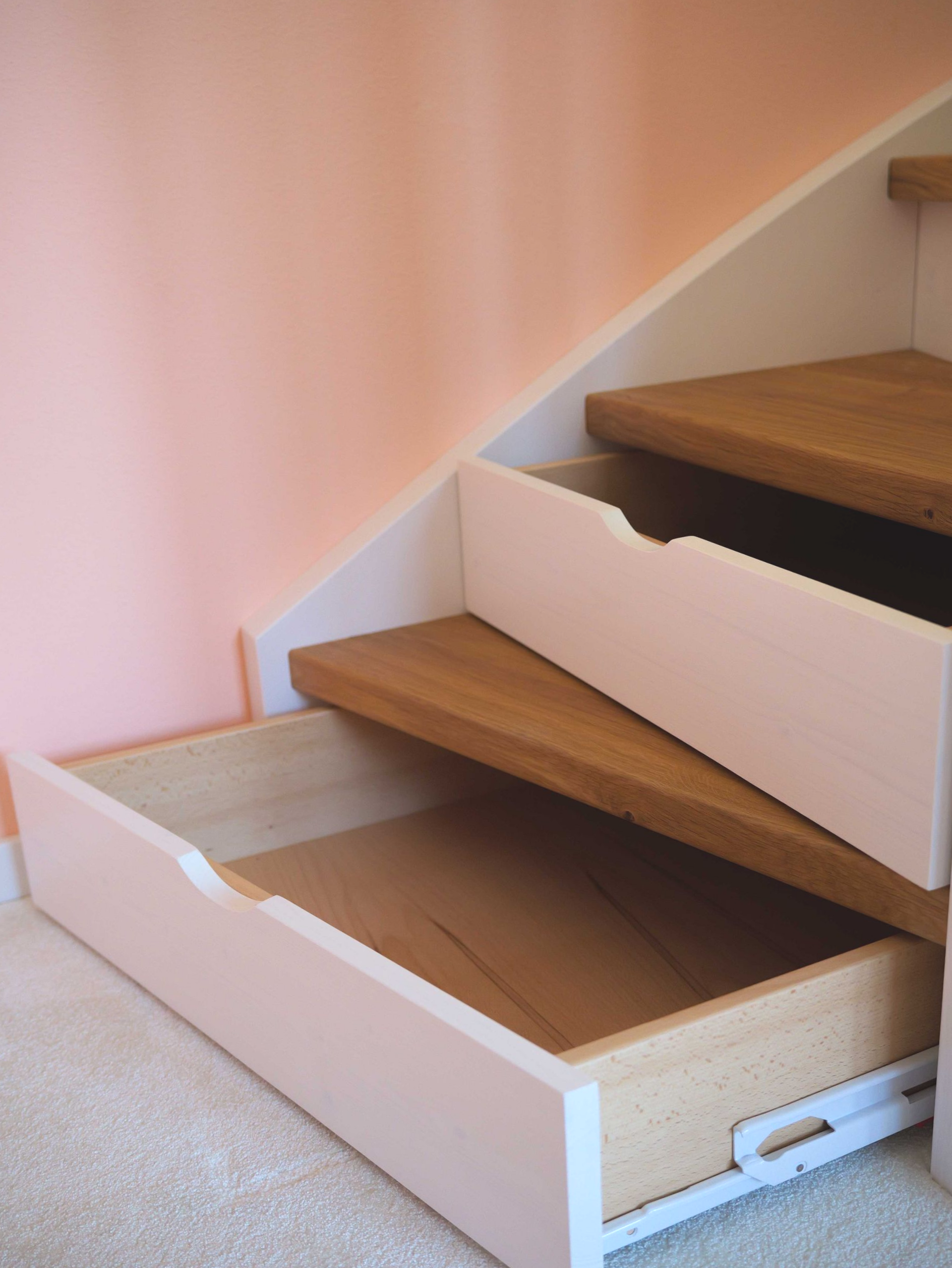 Treppe mit weißen Sicherheitsgeländern und Holzstufen in einem Wohnhaus.