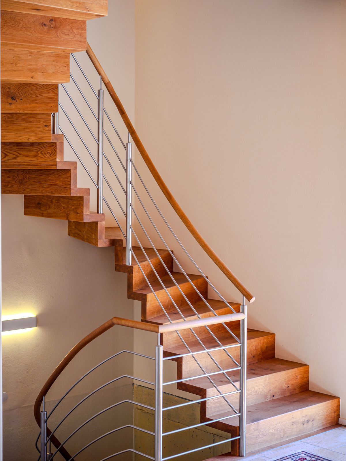 Geschwungene Treppe mit Holzstufen, Metallgeländer und Teppichboden in einem beigen Interieur