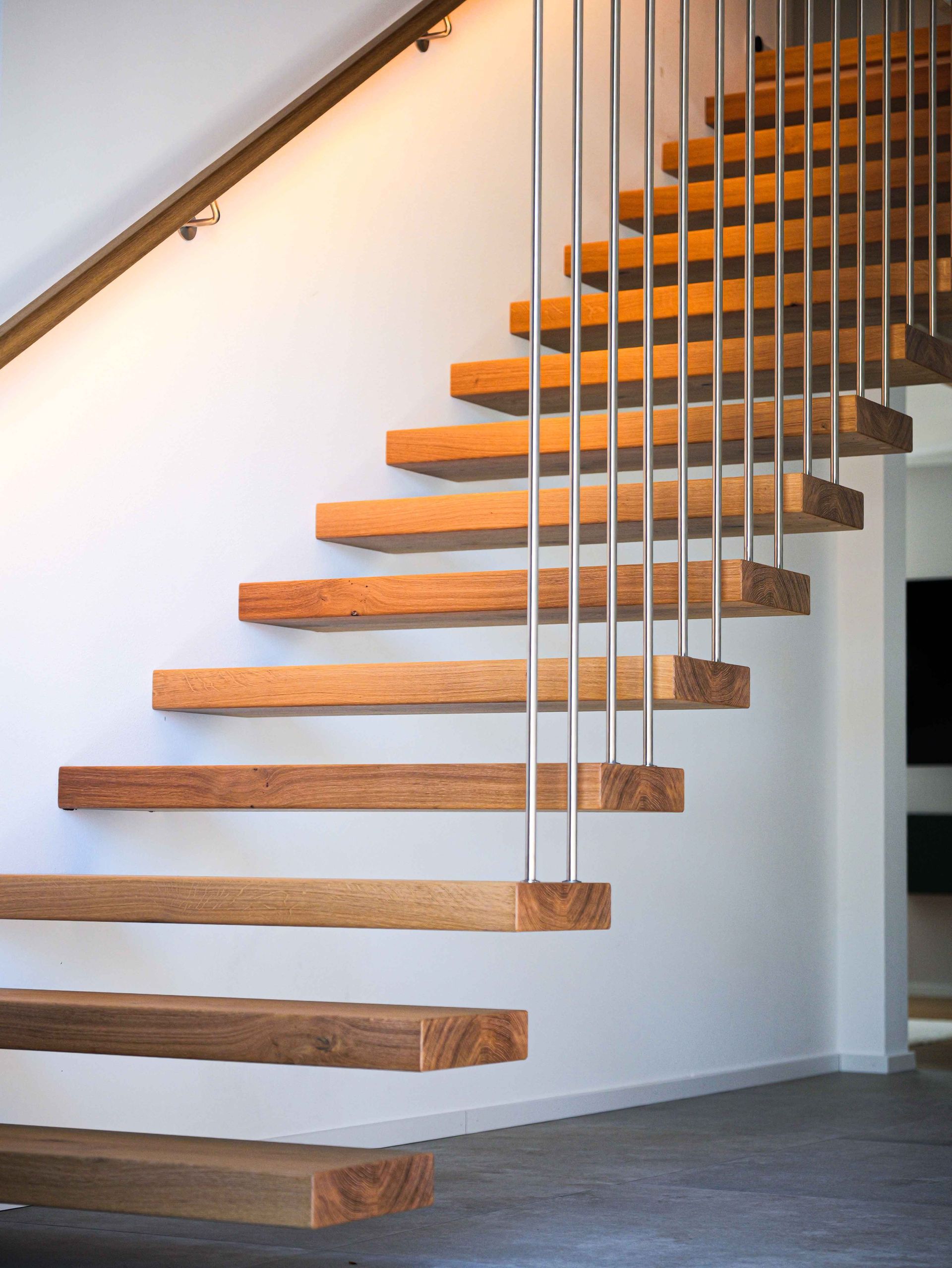 Freitragende Holztreppe mit offenen Stufen und Kabelgeländer in einem modernen Interieur