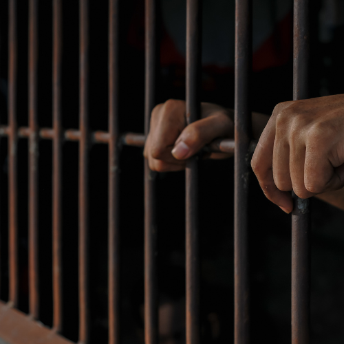 Hands gripping prison bars.