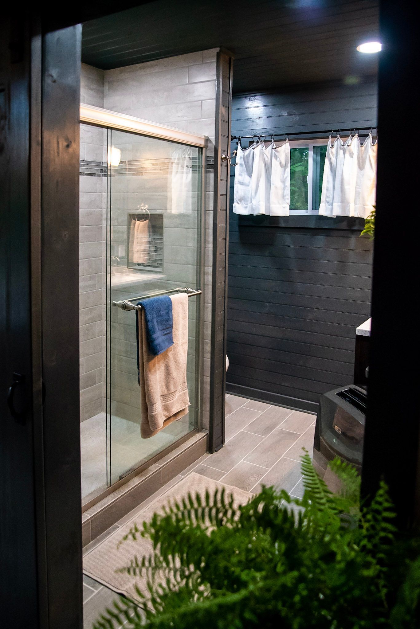 A bathroom with a walk in shower and a window.