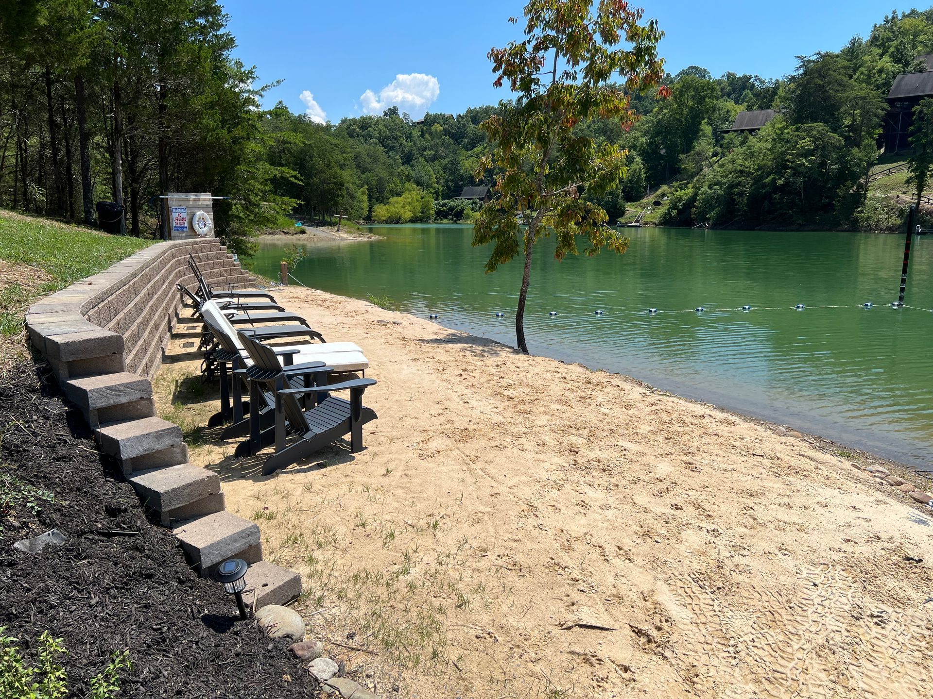 A picnic table is sitting on a sandy beach next to a lake.