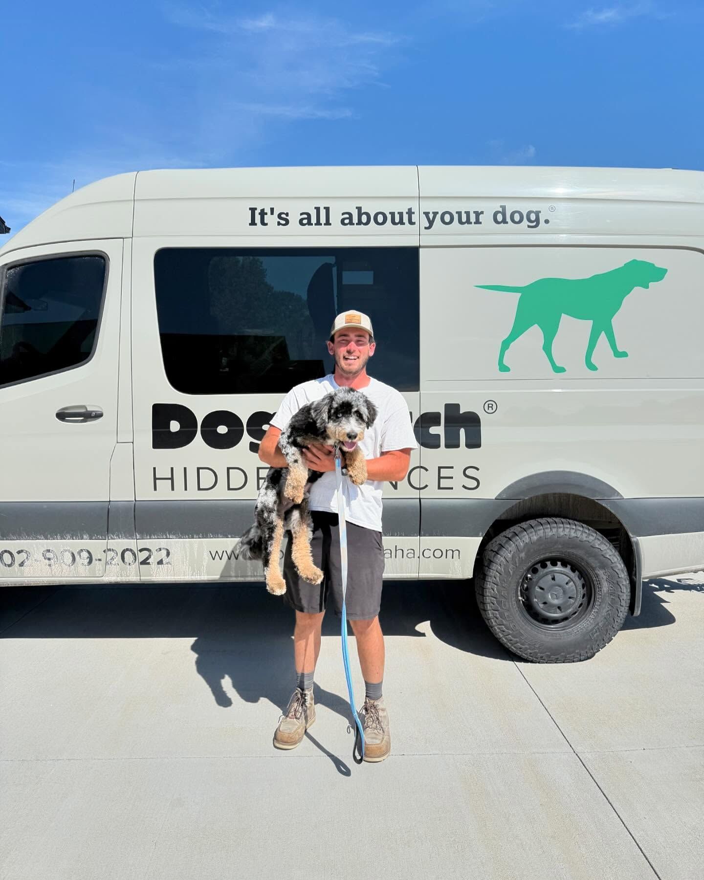Man holding a puppy next to a DogWatch van with the slogan