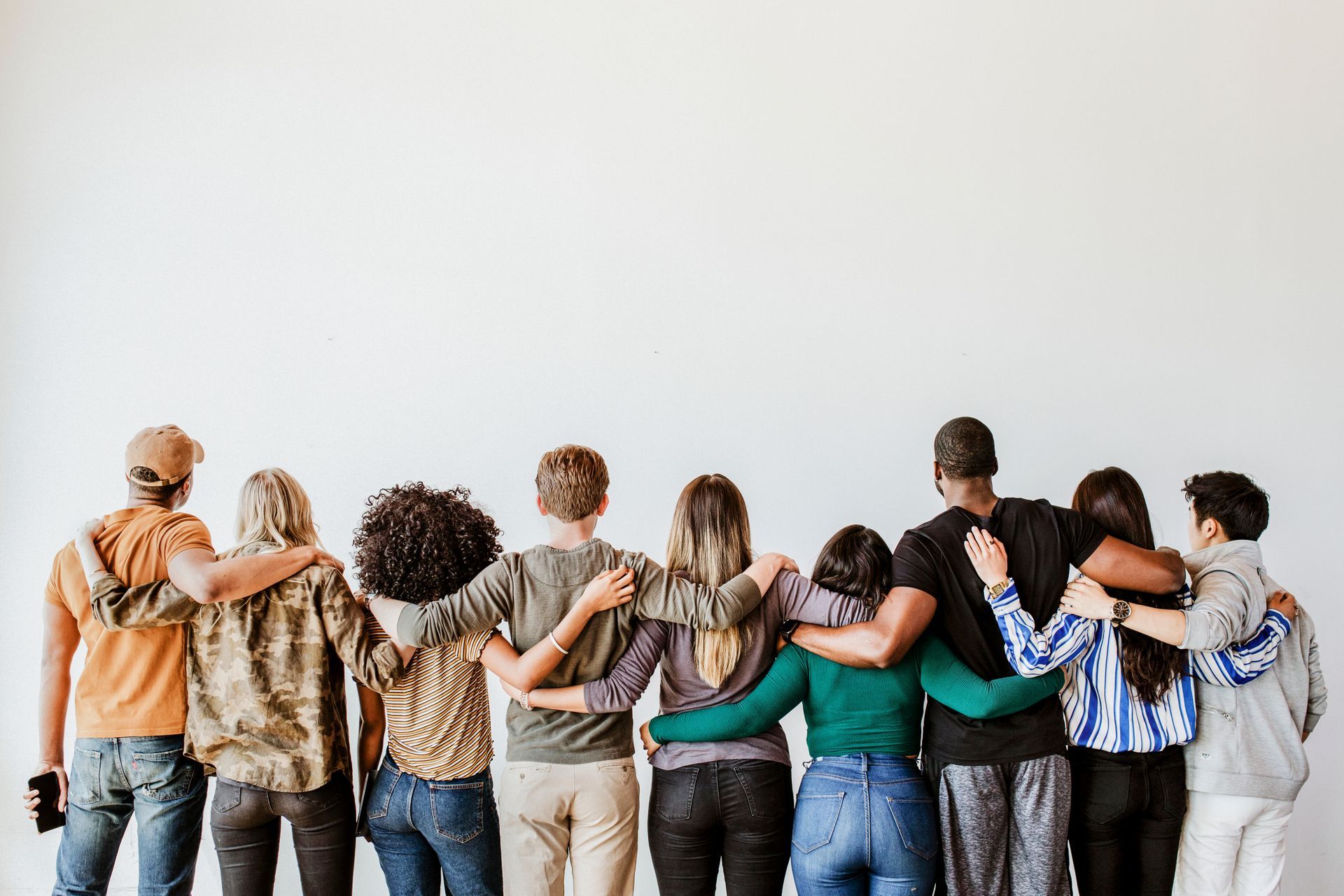 A group of people are standing next to each other with their arms around each other.