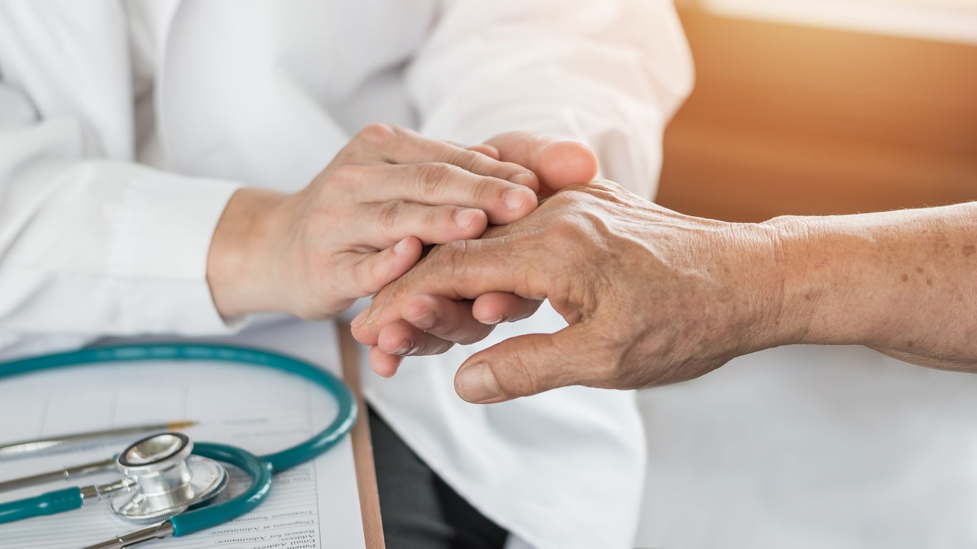 A doctor is holding the hand of an elderly patient.