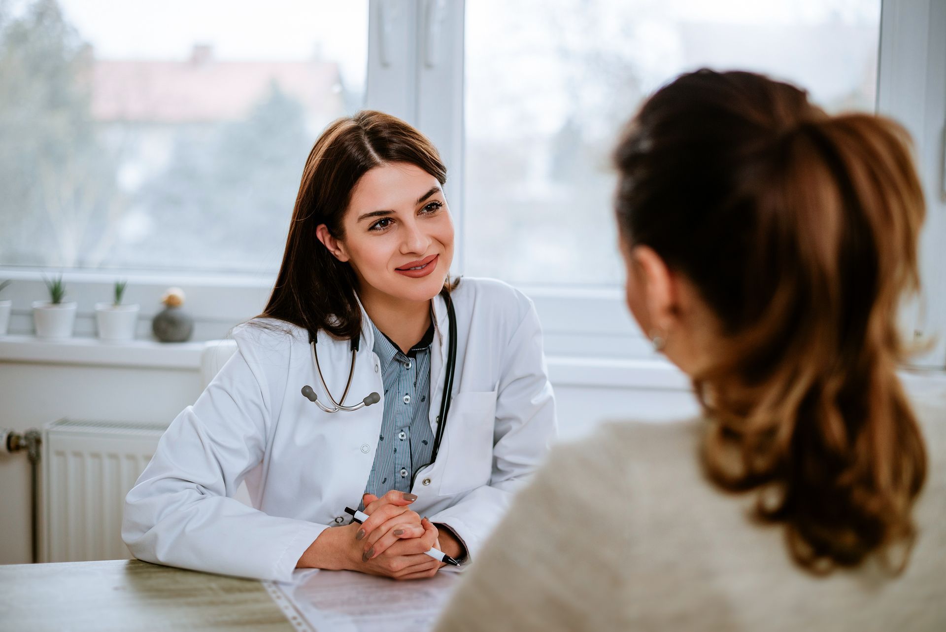 A female doctor is sitting at a table talking to a patient.