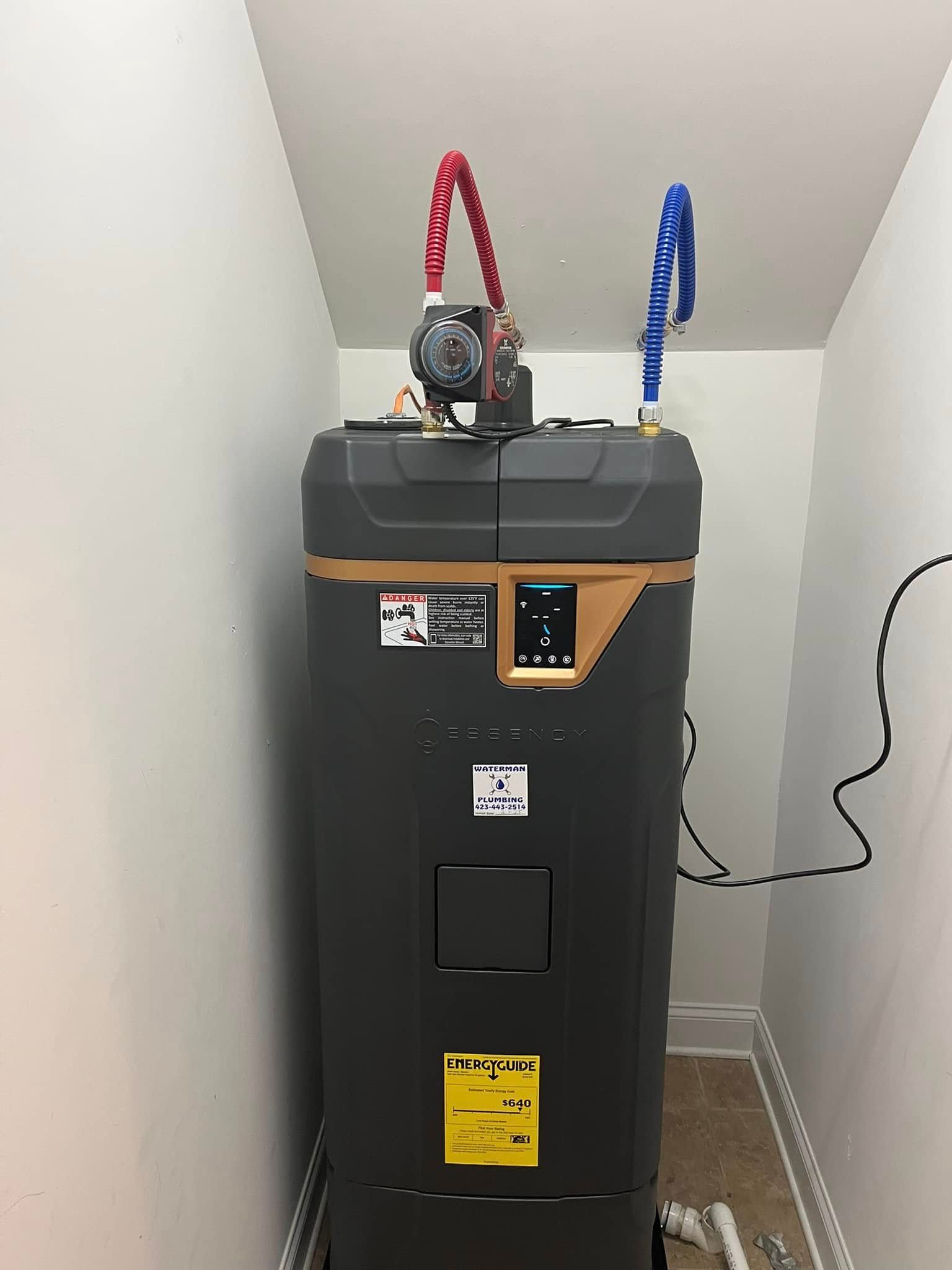 A tall, dark water heater with red and blue pipes is installed in a white-walled utility closet.