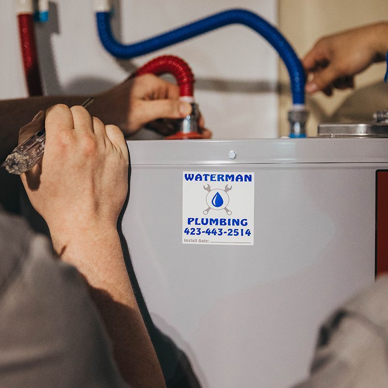 Two plumbers installing water pipes on a water heater, with a 