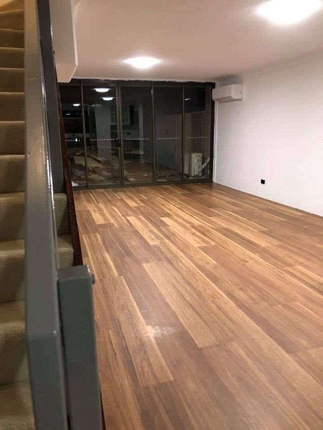 A Large Empty Room With Wooden Floors — Canberra Floor Coverings in Bungendore, NSW