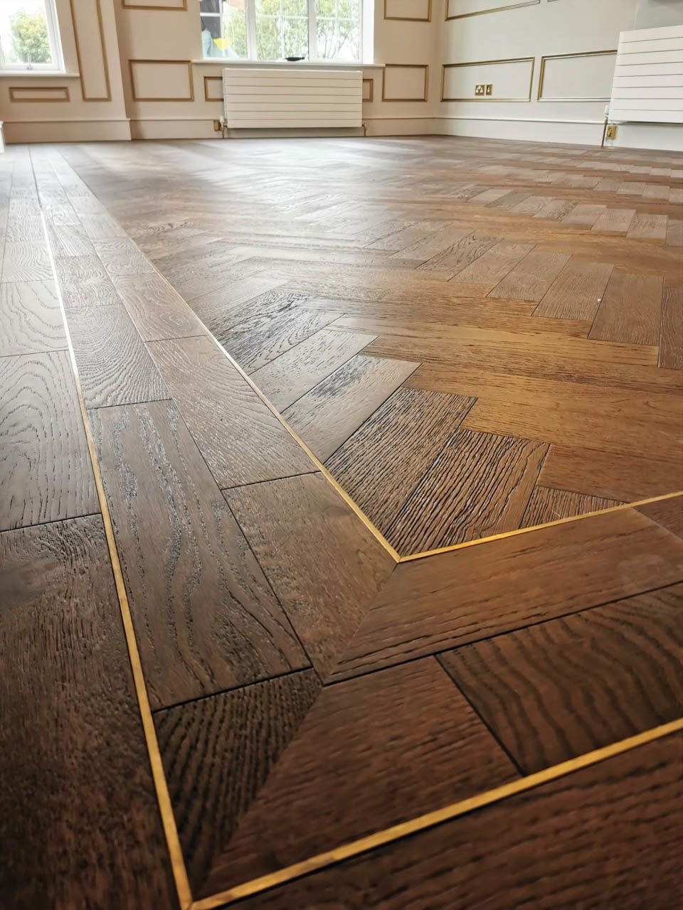 Close-Up of Dark Brown Parquet Wood Flooring with A Brass Border in A Room — Canberra Floor Coverings in Queanbeyan West, NSW