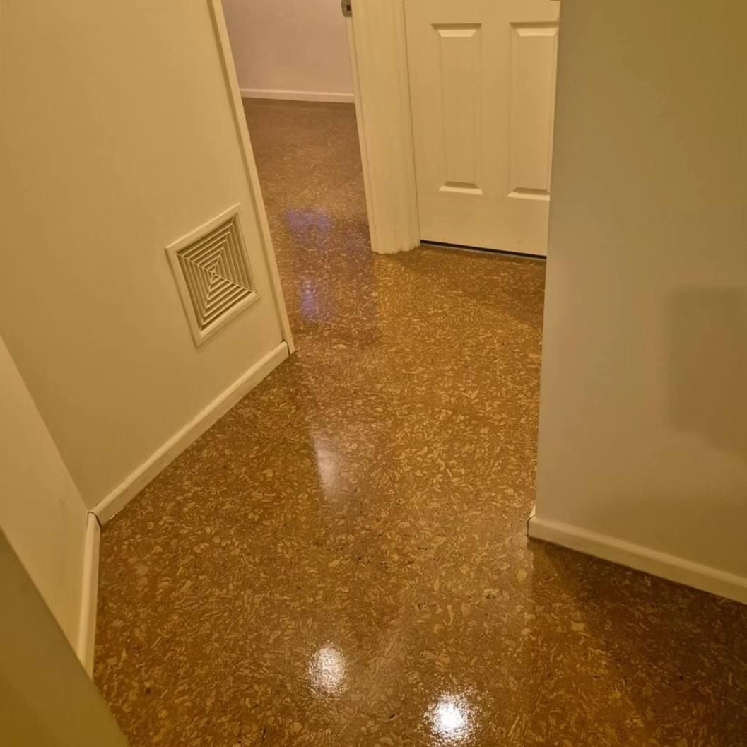 Hallway with Speckled Brown Flooring, White Walls, and A Closed White Door — Canberra Floor Coverings in Queanbeyan West, NSW