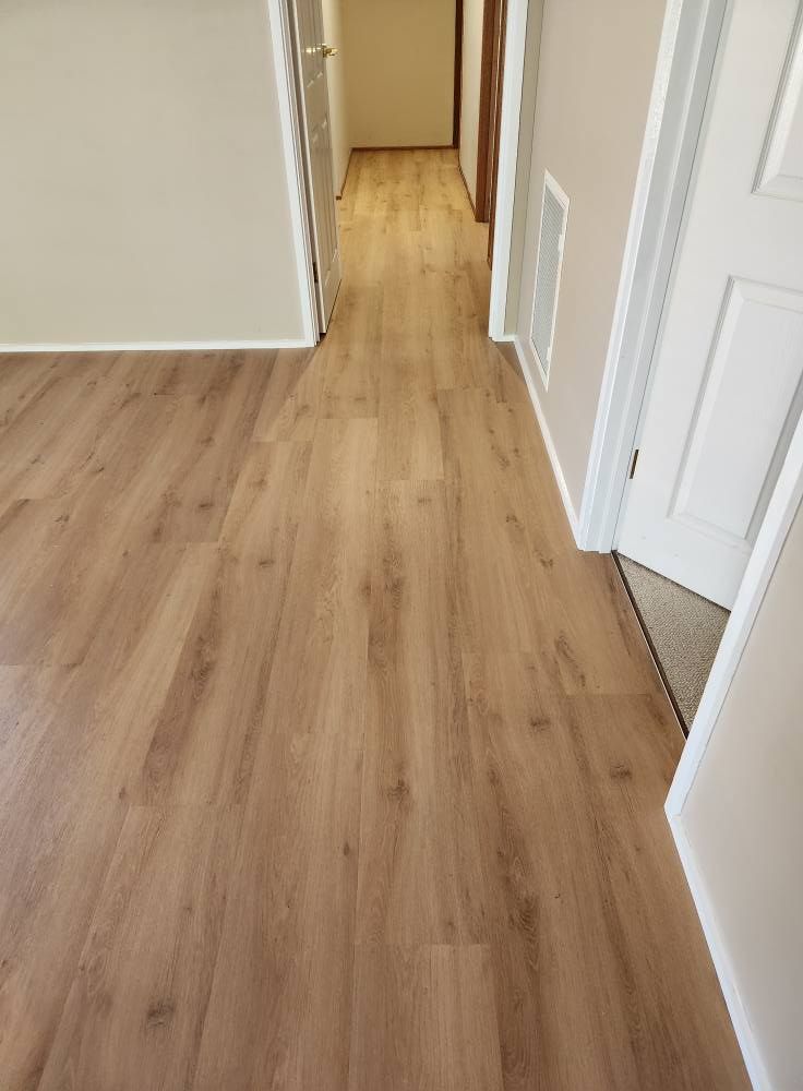 Wooden Floor in A Hallway, Leading to A Distant Room and Doorways. Beige Walls and White Trim — Canberra Floor Coverings in Queanbeyan West, NSW