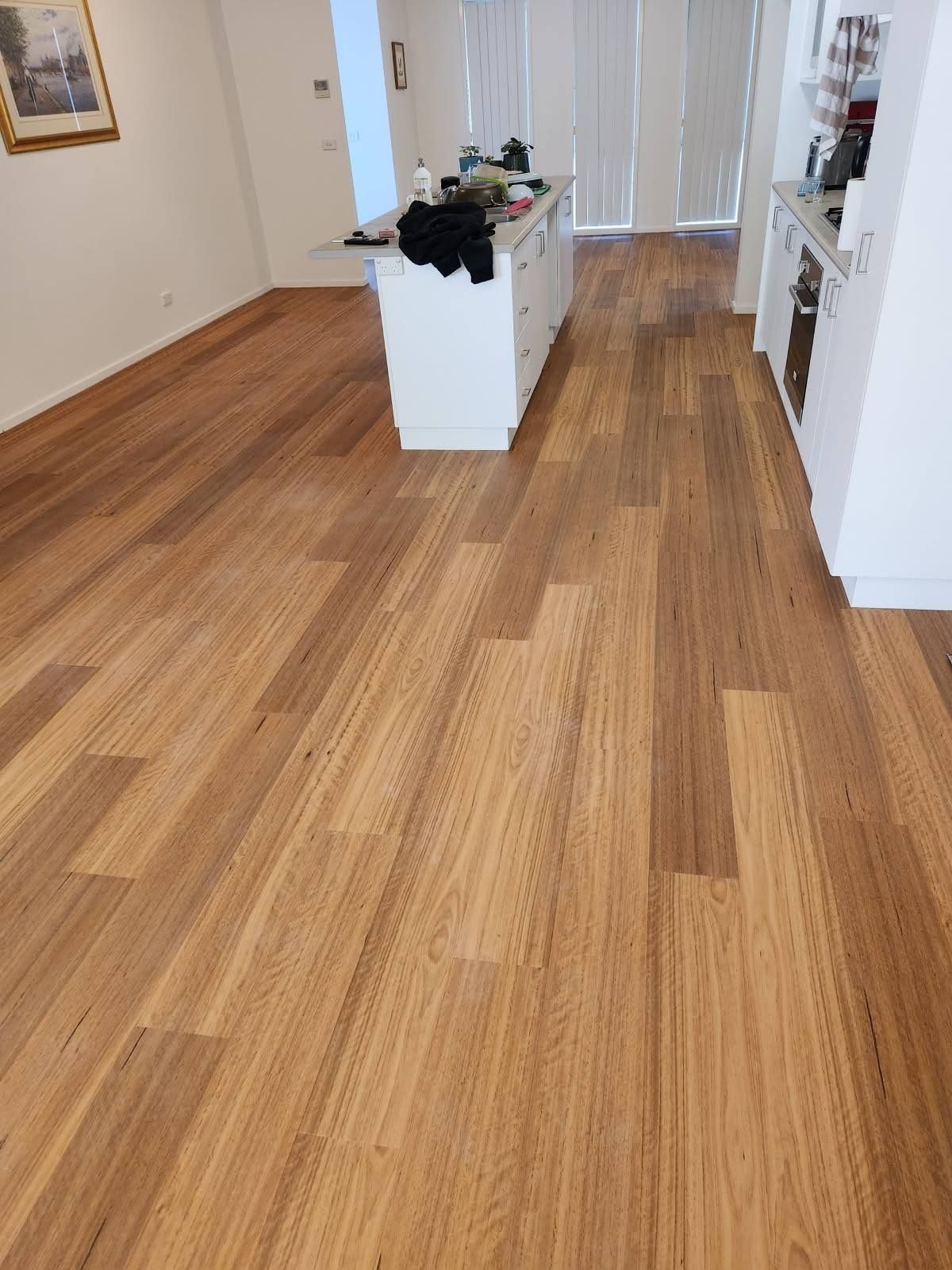 Wooden Floor in A Kitchen Area with White Cabinetry and A Kitchen Island — Canberra Floor Coverings in Queanbeyan West, NSW