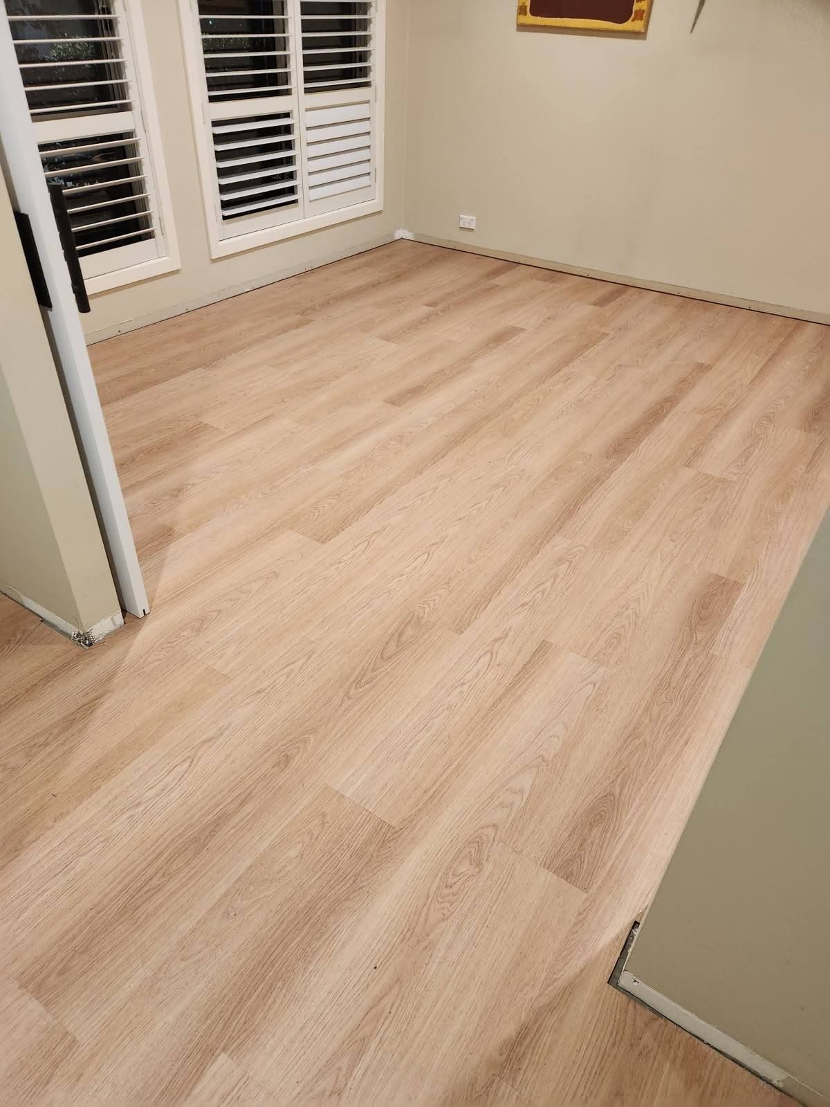 Empty Room with Light-Coloured Wood-Look Flooring and Neutral Walls — Canberra Floor Coverings in Queanbeyan West, NSW