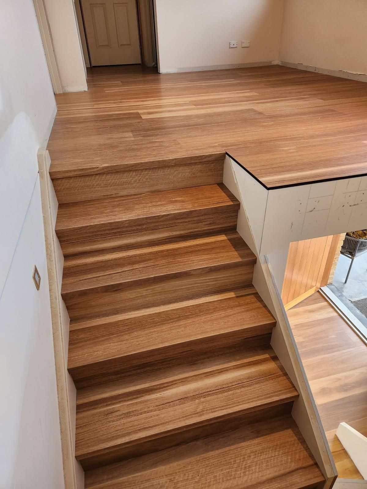 Wooden Stairs Leading to A Raised Wooden Floor. the Stairs Are Bordered by White Walls — Canberra Floor Coverings in Queanbeyan West, NSW