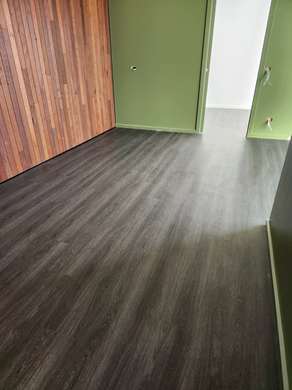 Room with Dark Grey Wood-Look Flooring, Green Walls, and Wooden Wall Paneling — Canberra Floor Coverings in Queanbeyan West, NSW