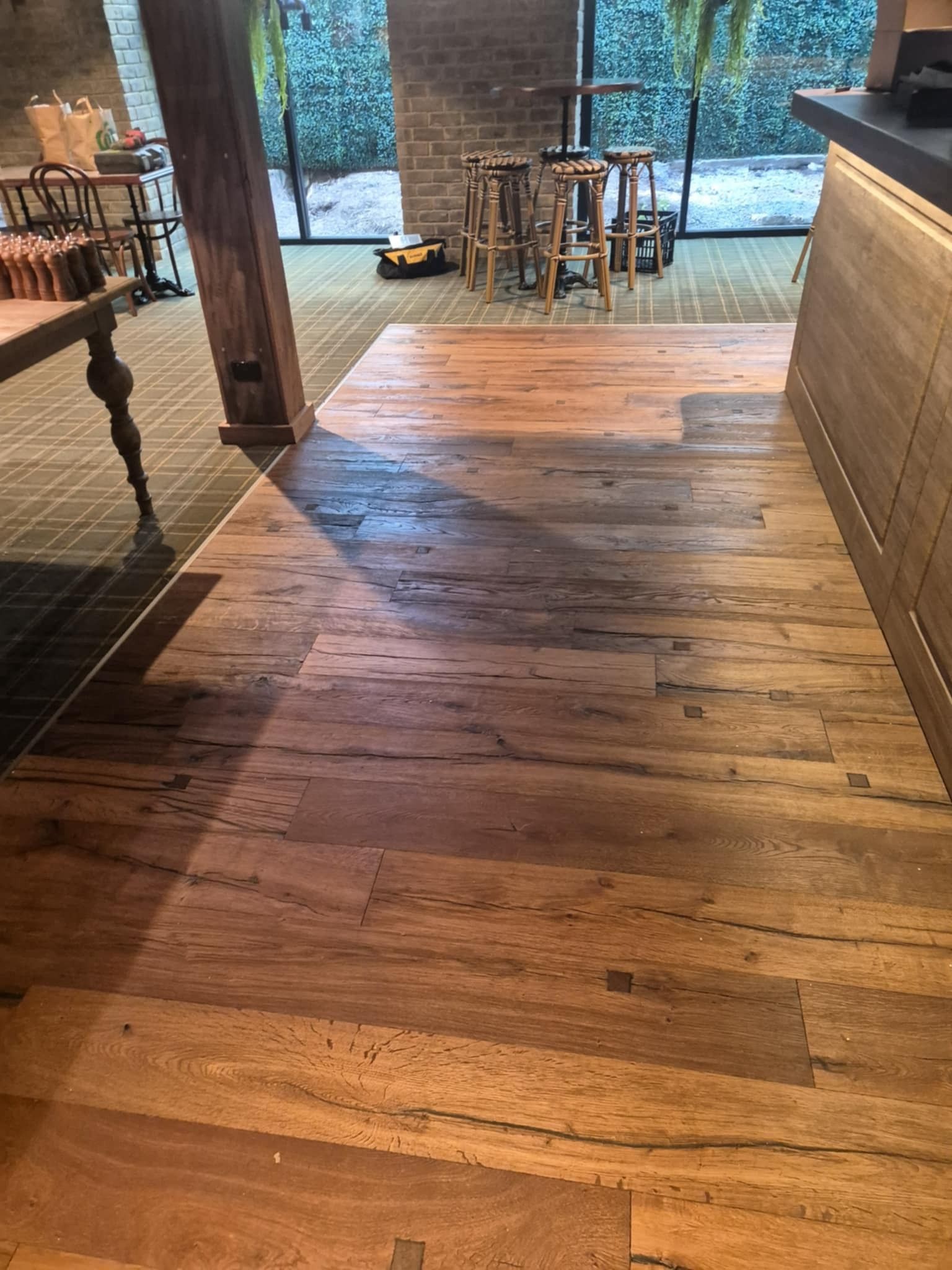 Wooden Floor in A Room with A Bar, Stools, and A View of Greenery — Canberra Floor Coverings in Queanbeyan West, NSW
