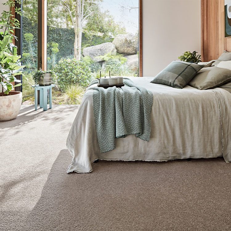 Bedroom With a Bed, Window View of a Garden and Beige Carpet — Canberra Floor Coverings in Queanbeyan, NSW