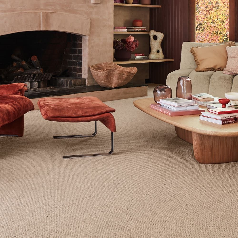 Beige carpeted living room with fireplace, velvet seating, and coffee table.