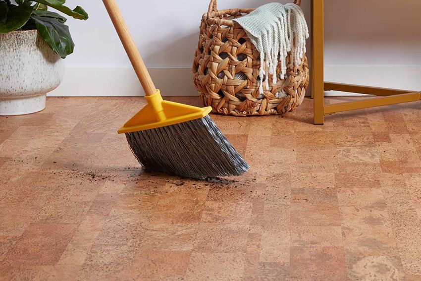 A Person is Sweeping a Cork Floor With a Broom — Canberra Floor Coverings in Googong, NSW