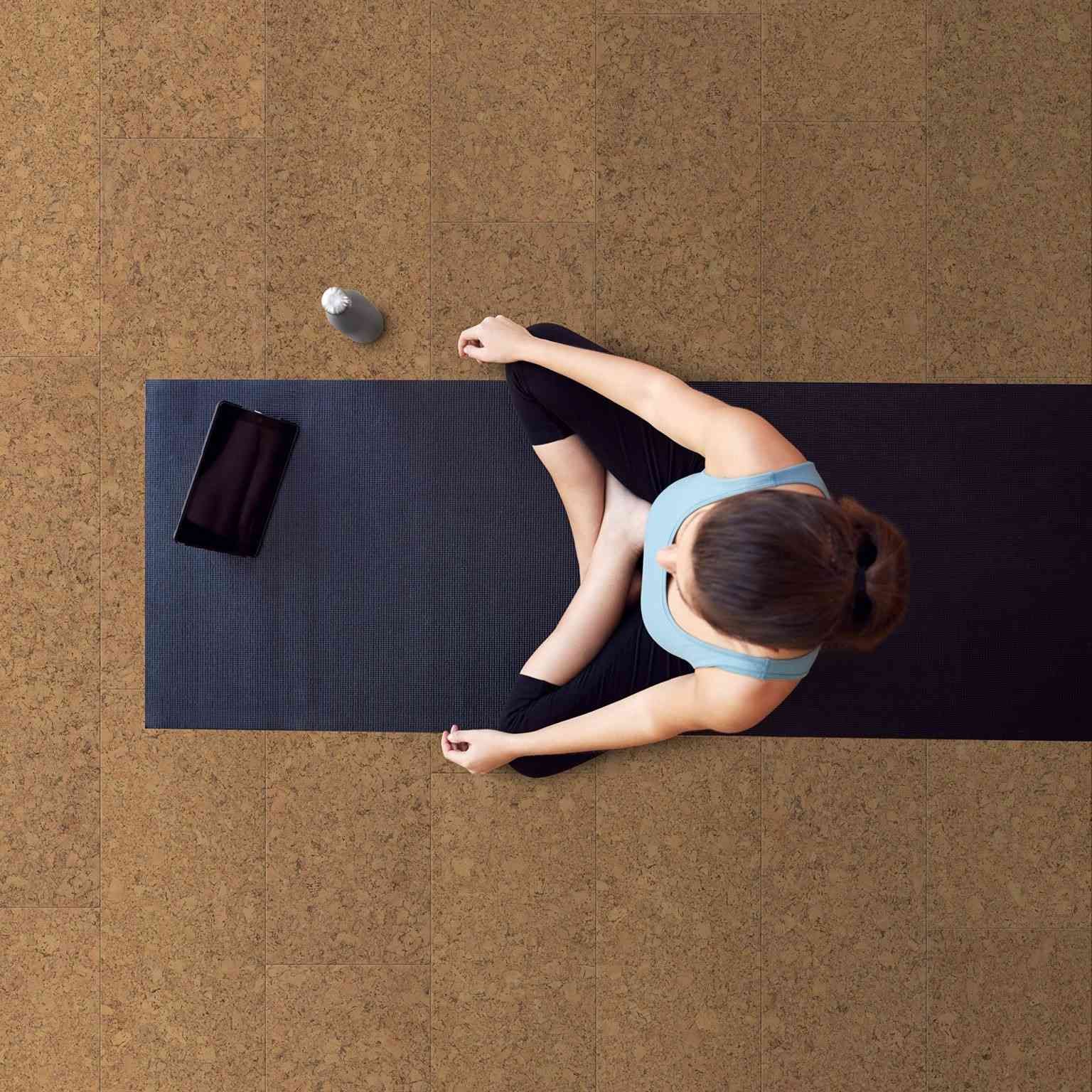 Woman Sitting on Yoga Mat with Tablet and Water Bottle — Canberra Floor Coverings in Queanbeyan West, NSW