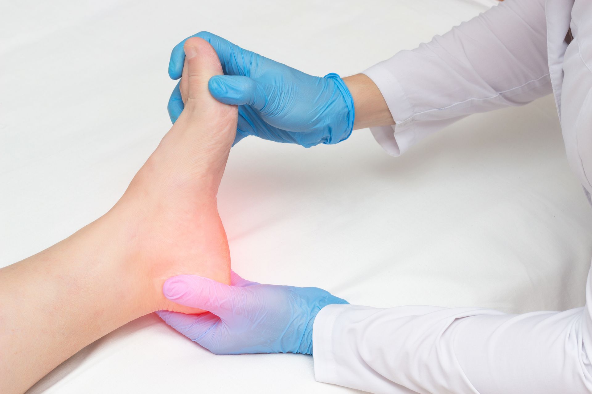 Medical professional examining a foot, highlighting pain area.