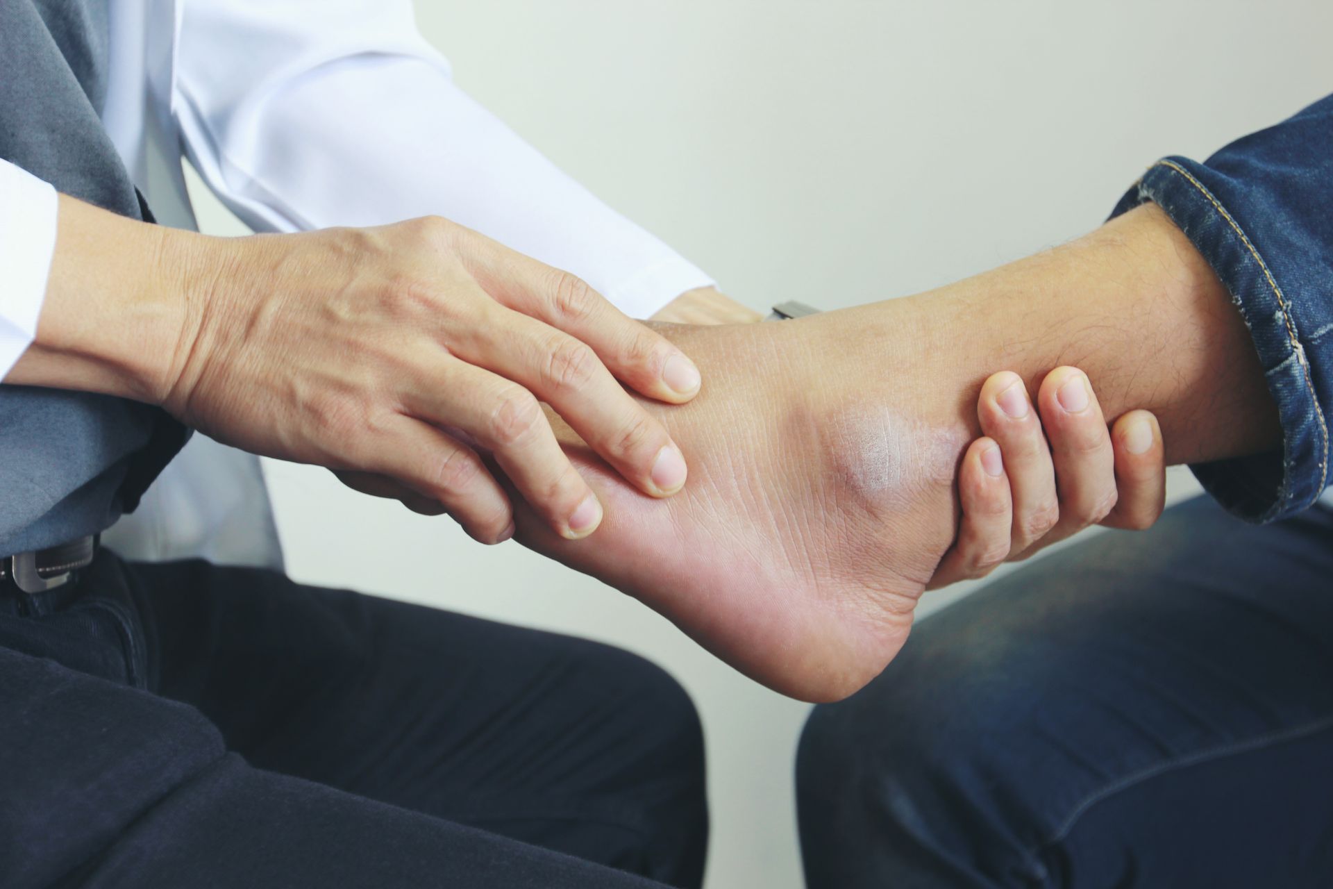Doctor examines a patient's swollen ankle, indoors.