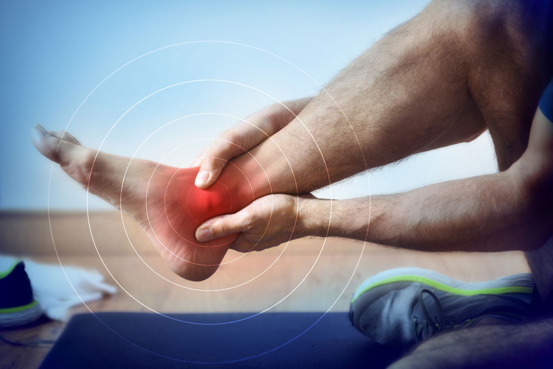 Man holding ankle in pain, red area highlights inflammation, possibly a sprain.