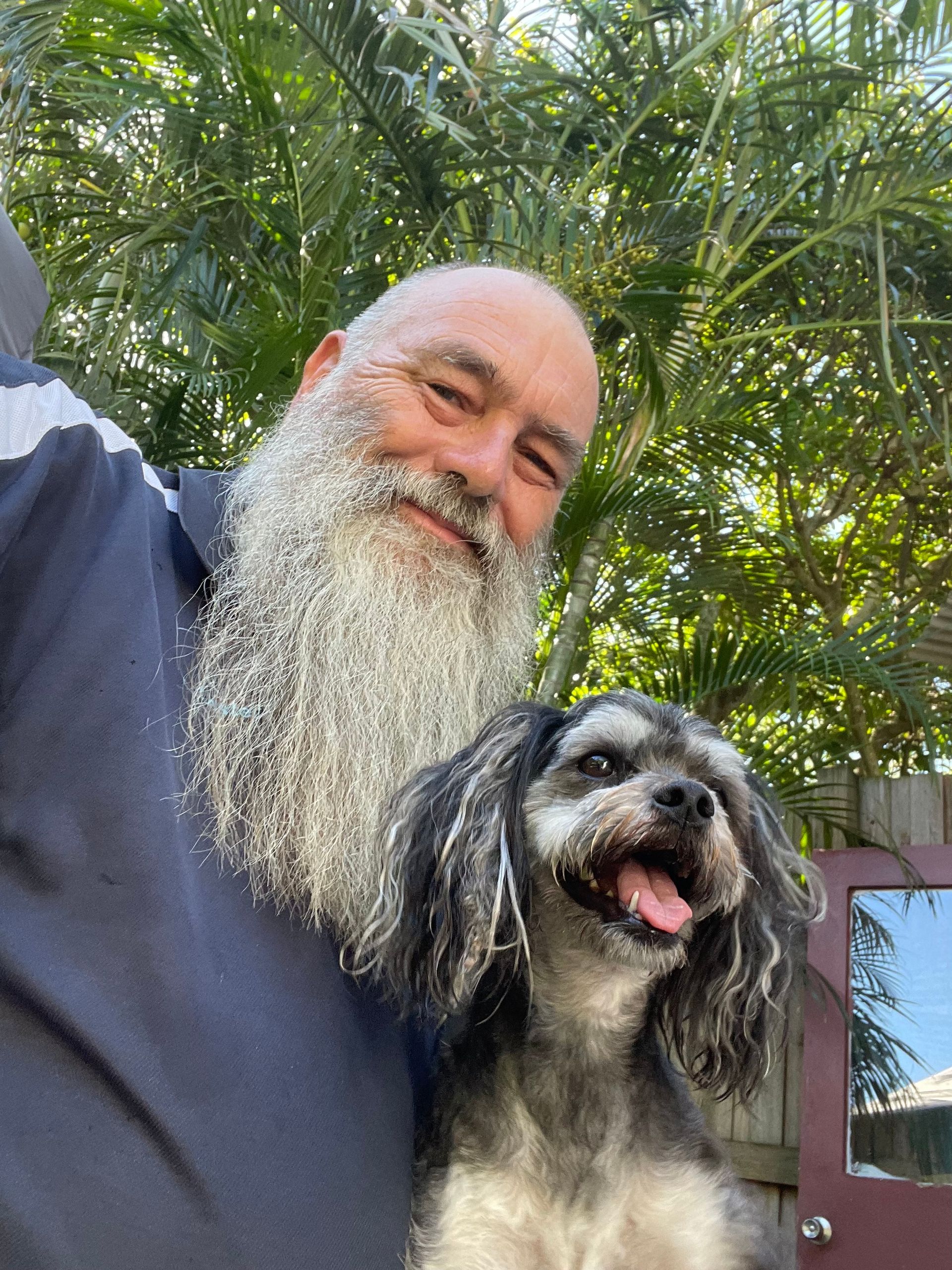 A Man With A Beard Is Holding A Small Dog — Yeppoon Boarding Kennels & Cattery In Farnborough, QLD