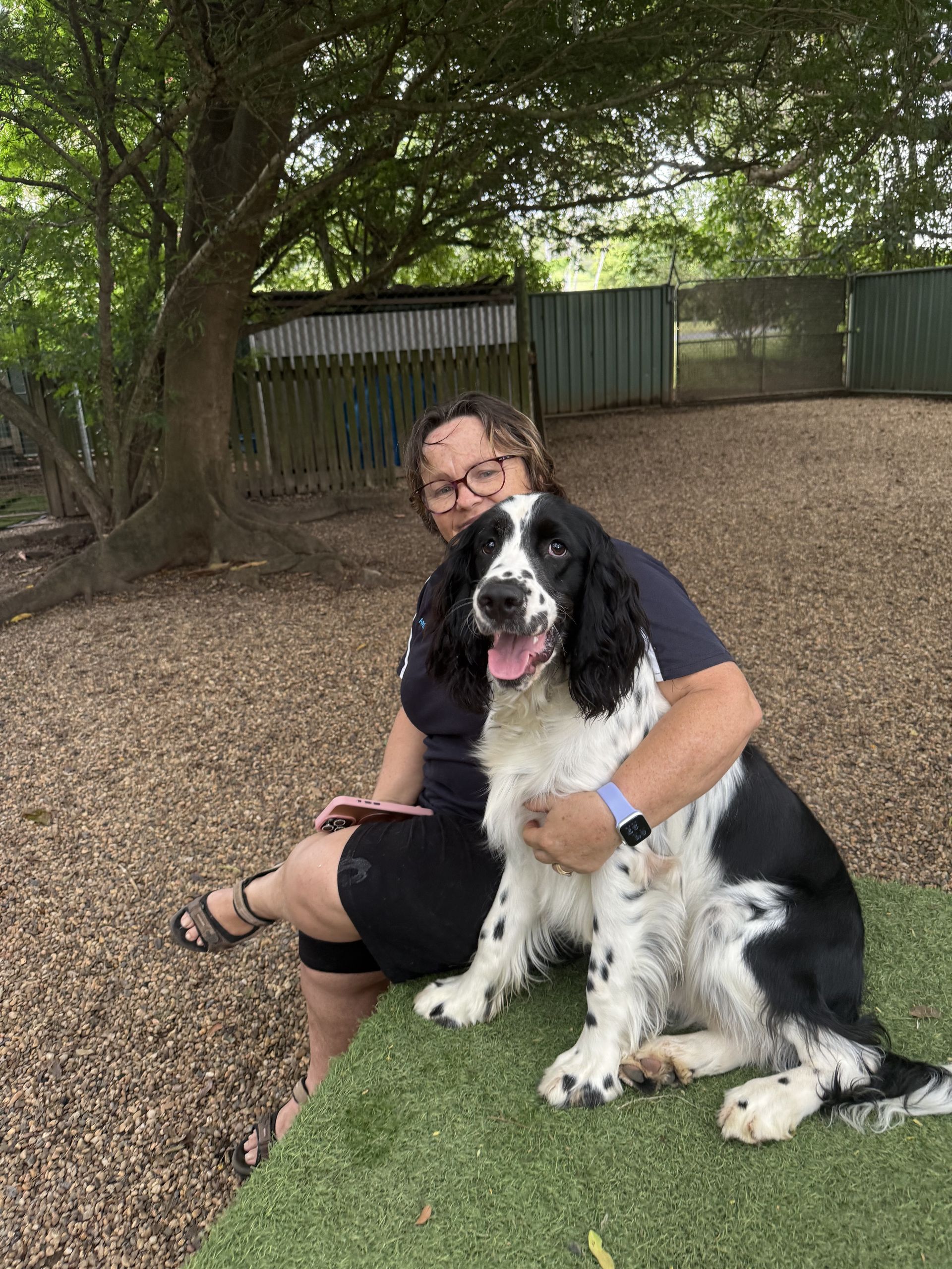 A Woman Is Sitting Down Holding A Dog — Yeppoon Boarding Kennels & Cattery In Farnborough, QLD