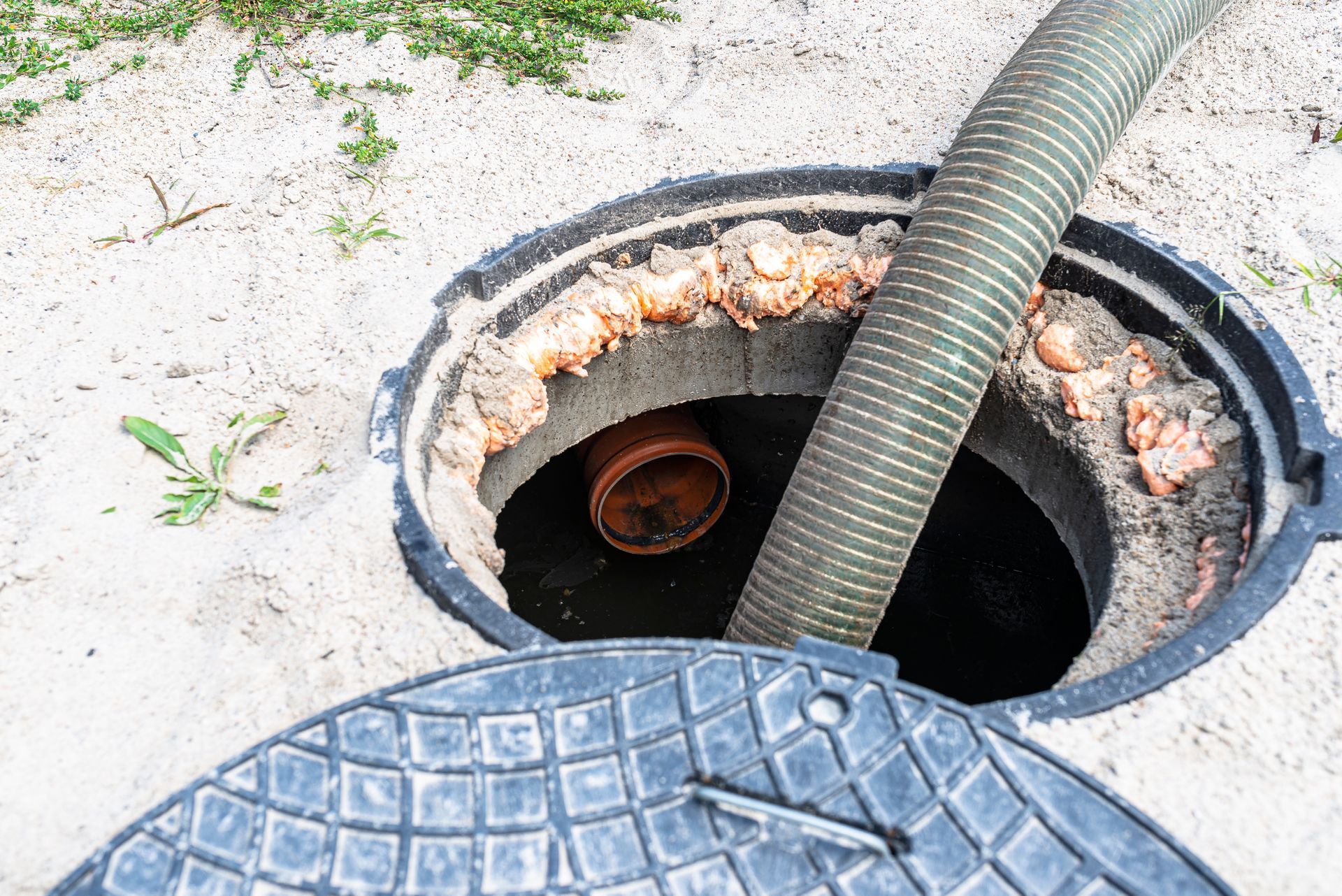 A manhole cover is open and a hose is coming out of it.