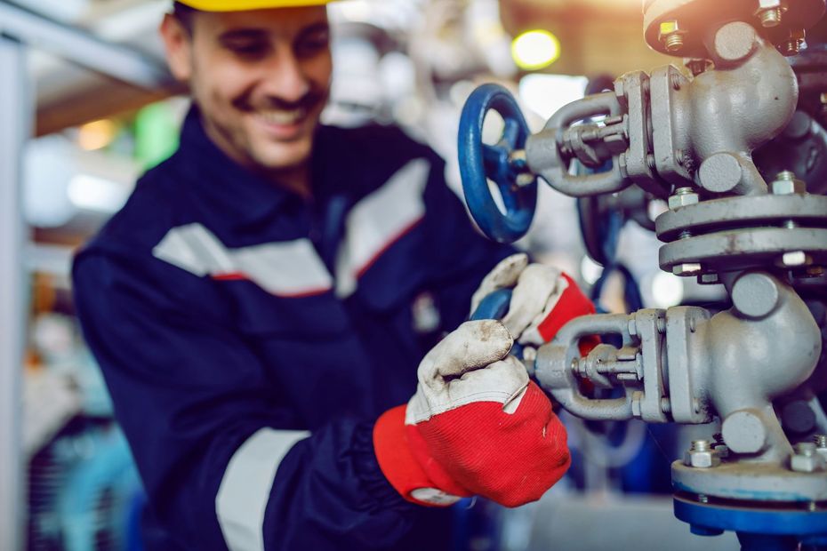 A man is working on a valve in a factory.