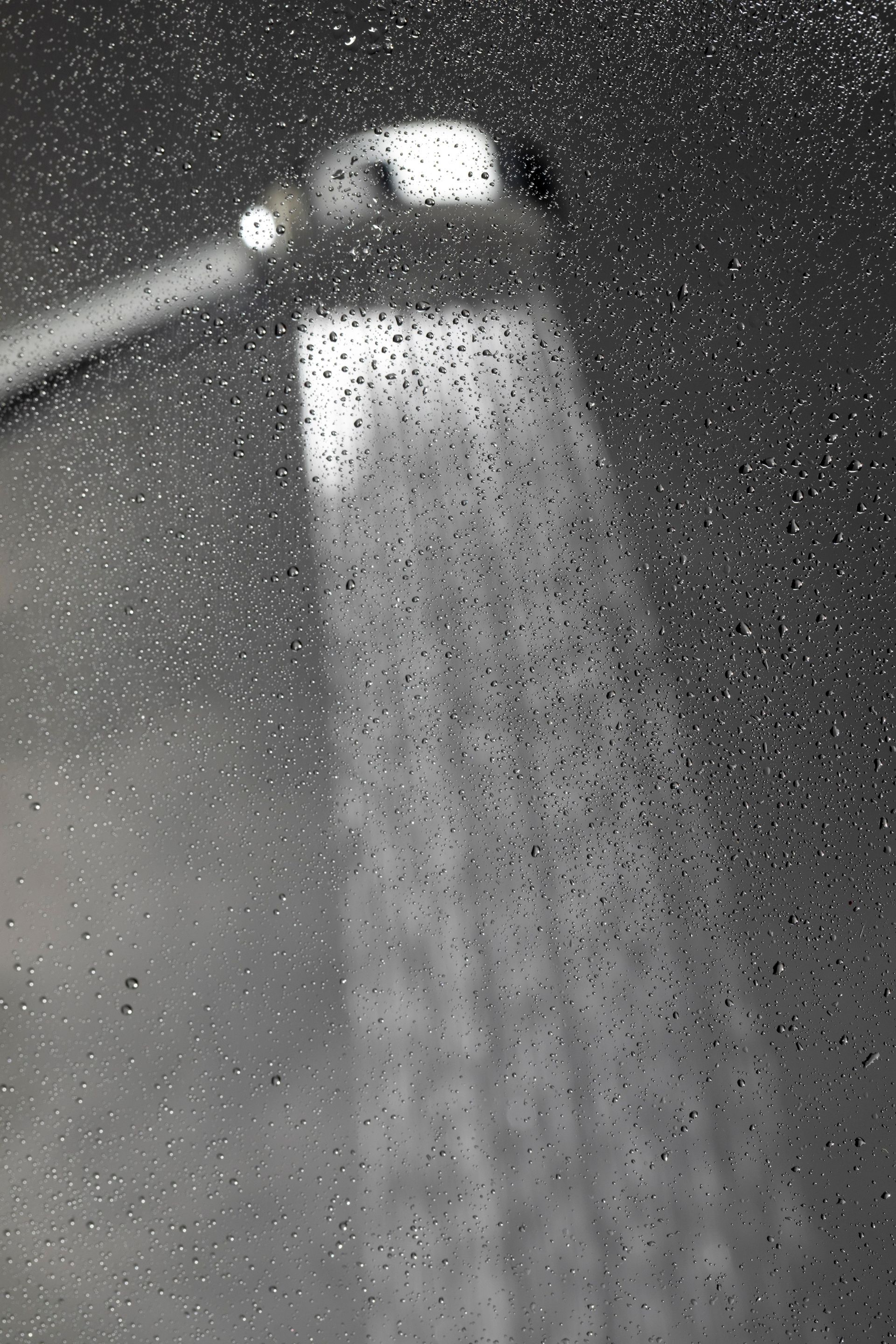A black and white photo of a shower head spraying water