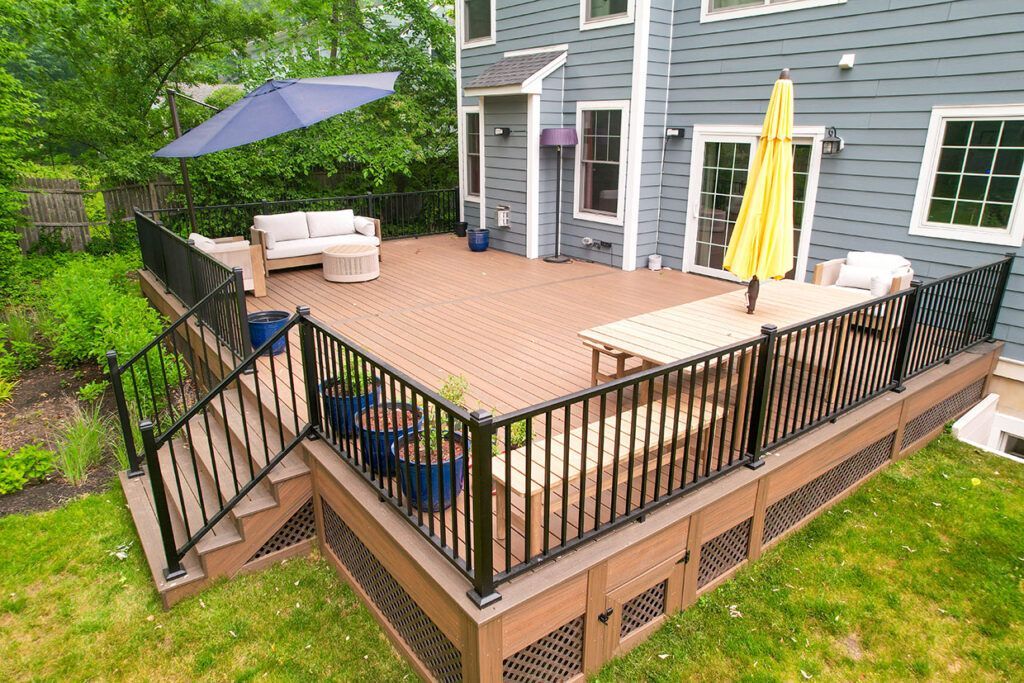 An aerial view of a large deck with a fence and umbrellas in front of a house.
