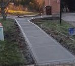 A concrete walkway is being built in front of a house.