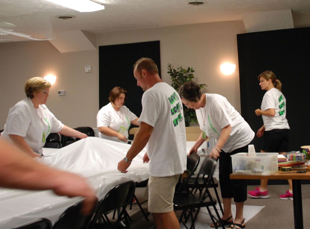 A group of people are gathered in a room and one of them is wearing a shirt that says i love you