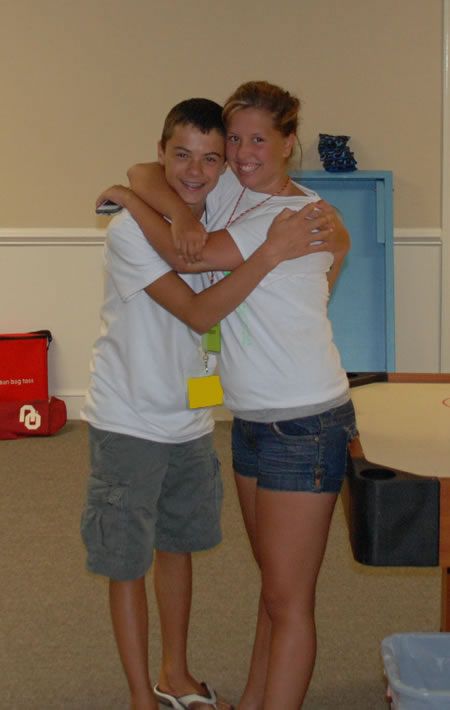 A boy and a girl are hugging each other in a room