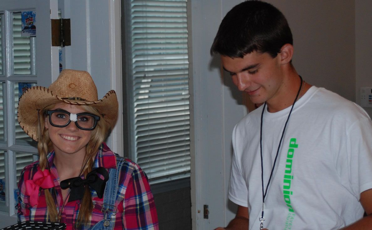 A man and a woman are standing next to each other and the woman is wearing a cowboy hat and glasses