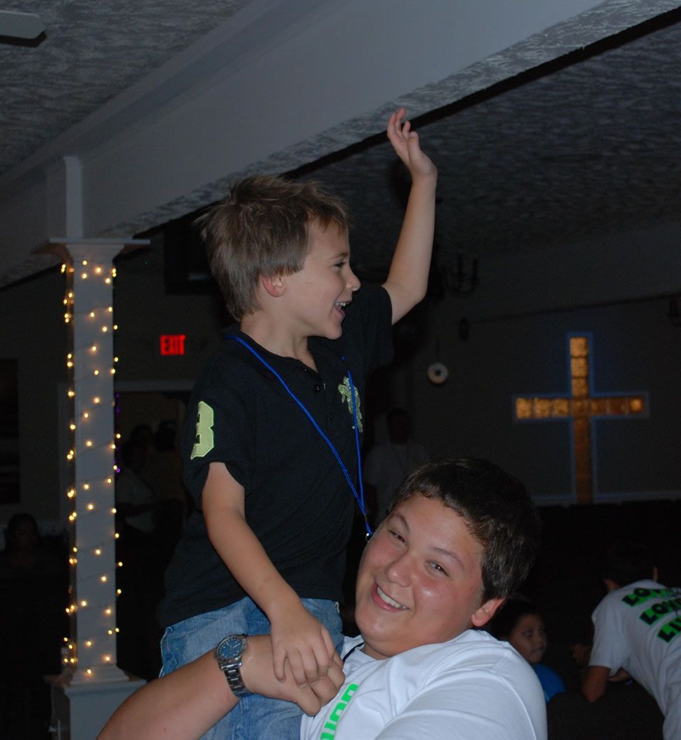 A boy in a black shirt is sitting on a man 's shoulders