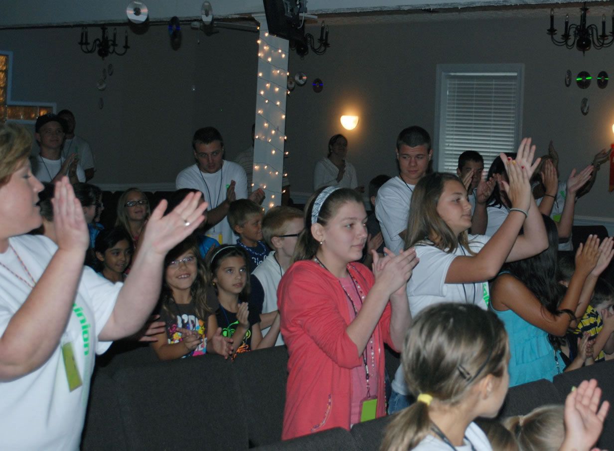 A group of people are clapping their hands in a room