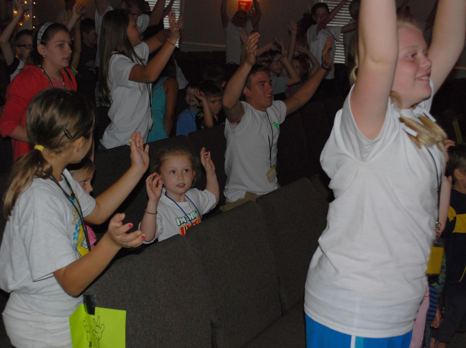 A group of children are standing in a room with their arms in the air